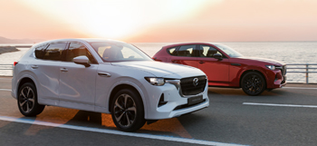 Two all-new Mazda CX-60 Plug-In Hybrid SUVs driving down the highway.