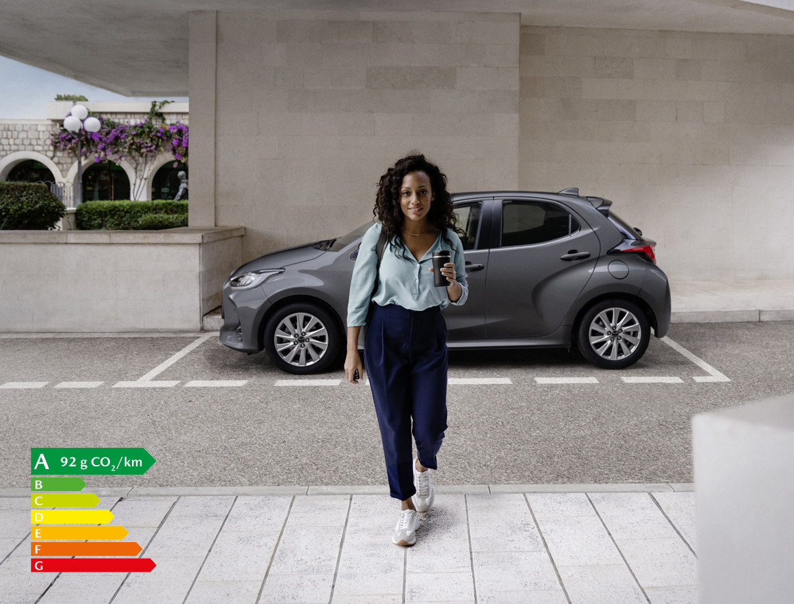 Femme marchant devant la Mazda2 Hybrid