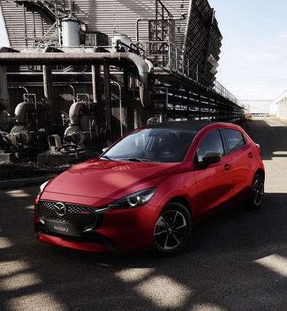 Ein roter Mazda2, von vorne abgebildet in einer Industrieumgebung.
