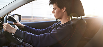 A young man pictured inside the Mazda 2 driving down a road.