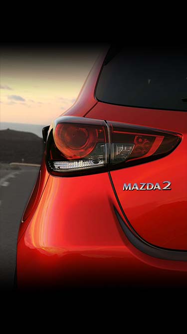 Izgled zadnjih kombinovanih svetala na crvenom automobilu Mazda2 za 2023. izbliza.
