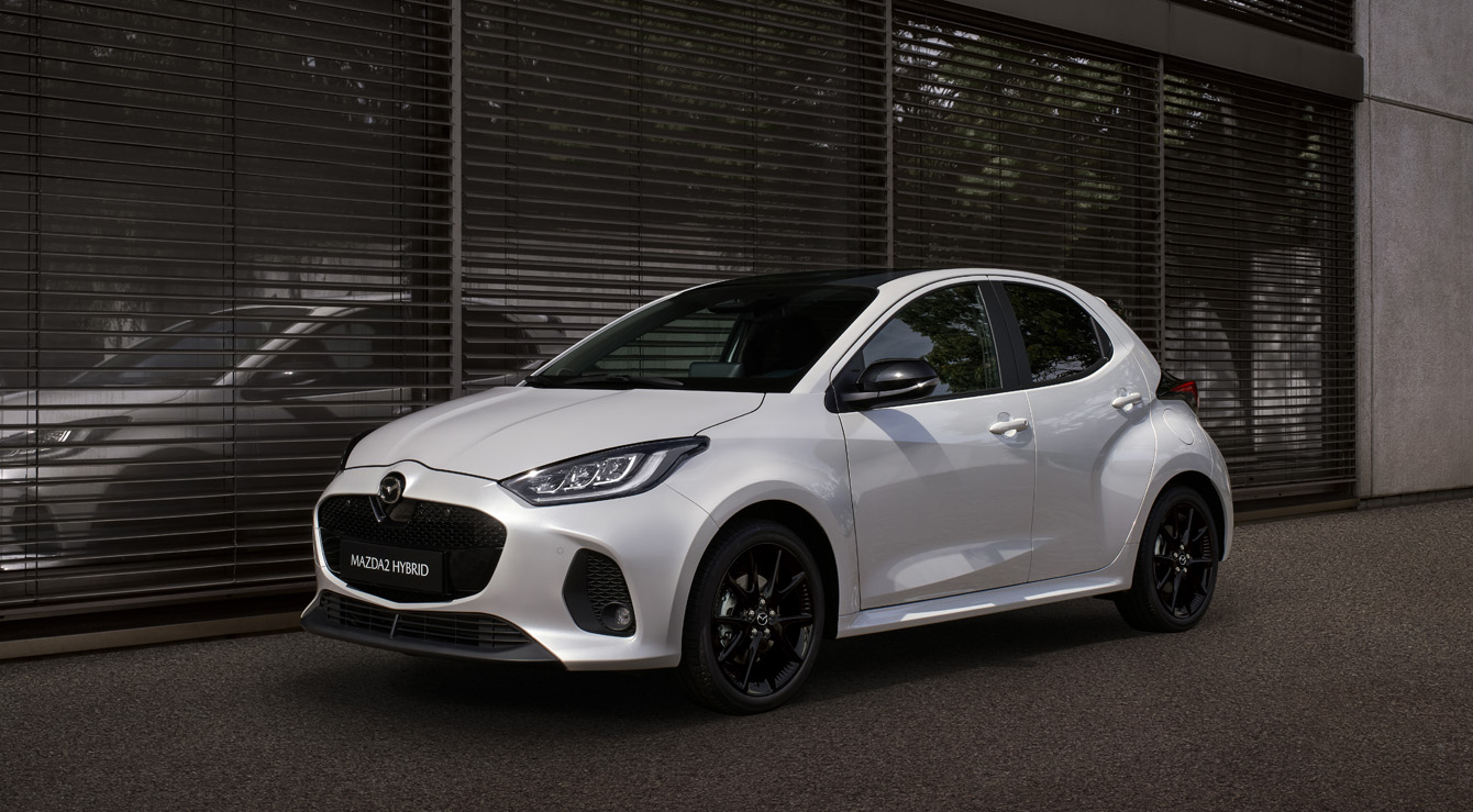 Mazda2 Hybrid i hvid parkeret foran en bygning.