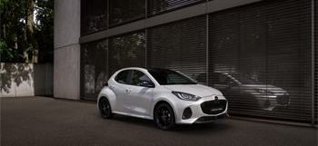 The Mazda2 Hybrid in white parked in front a building.