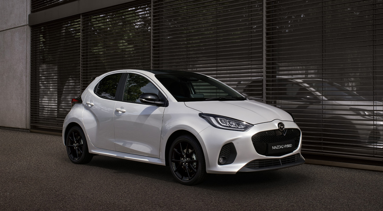 The Mazda2 Hybrid in white parked in front a building.