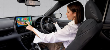 A woman using the touchscreen panel while driving the Mazda2 Hybrid.