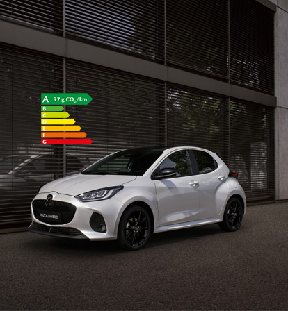 Mazda2 Hybrid de couleur blanche stationnée devant un bâtiment.