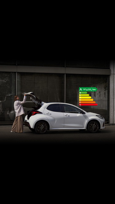 Femme ouvrant le coffre d’une Mazda2 Hybrid de couleur blanche.