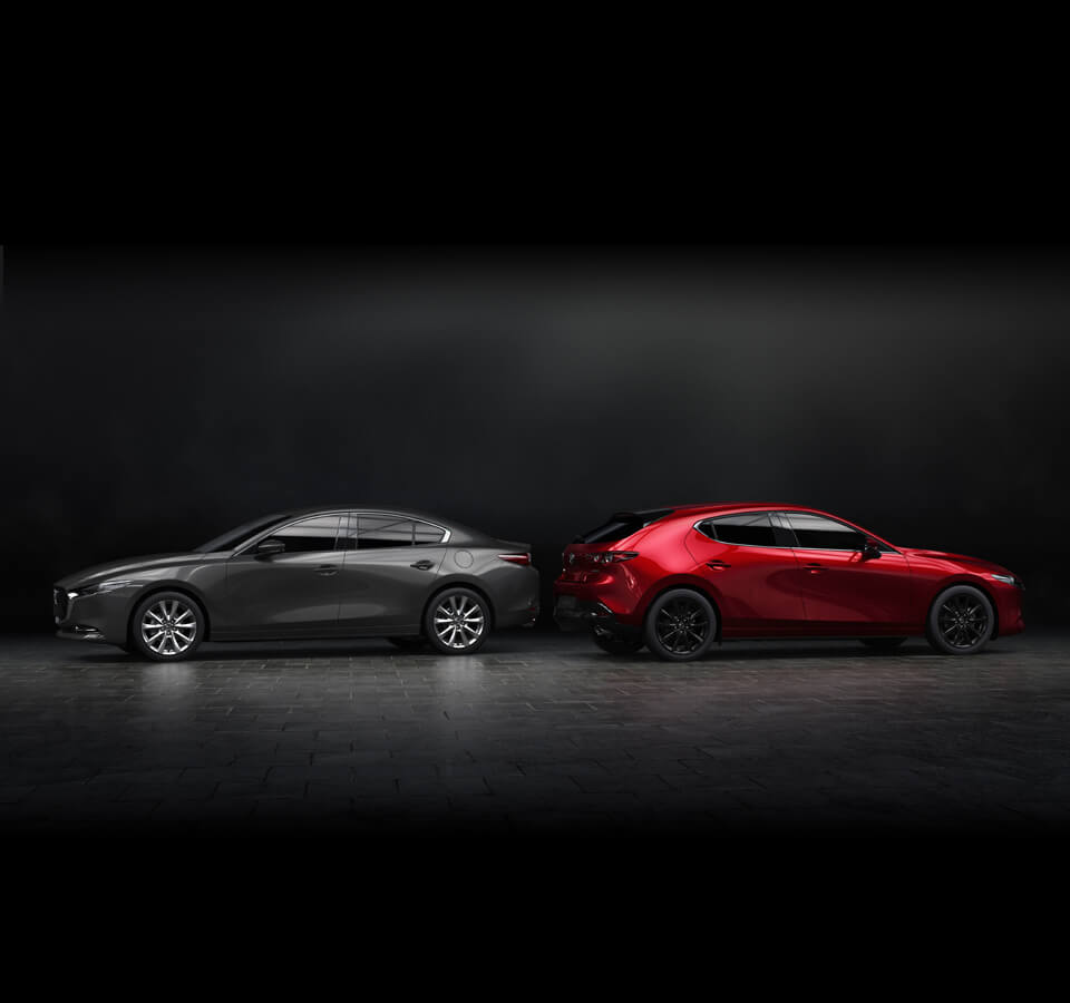 Šedá Mazda3 Sedan vedle červené Mazdy3 Hatchback na černém pozadí