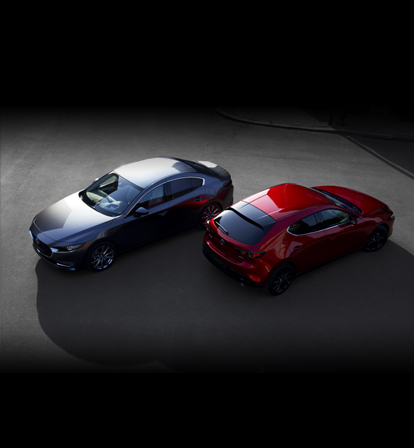 Ένα μαύρο Mazda3 Sedan στραμμένο προς τα εμπρός και ένα κόκκινο Mazda3 Hatchback όπως φαίνεται από πίσω.