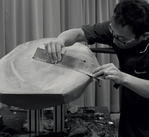 A Mazda master craftsmen, a Takumi, shaping the flowing lines of the Mazda3 by hand.