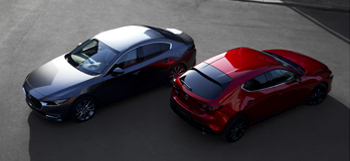 Een zwarte Mazda3 Sedan van de voorkant gezien en een rode Mazda3 Hatchback van de achterkant gezien.