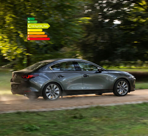 Mazda3 berline grise vue de profil sur une route de campagne.