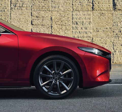 Close-up van een lichtmetalen velg van de rode Mazda3 Hatchback.