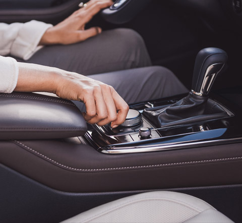 A woman’s hand using the HMI Commander dial with her arm resting on the wide centre armrest.