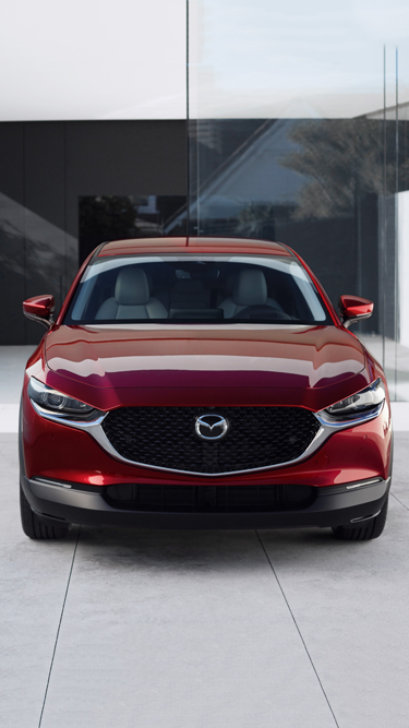 The front view of the new Mazda CX-30 in red parked inside a building.