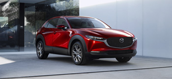 The front of the Mazda CX-30 parked in front of a glass door.