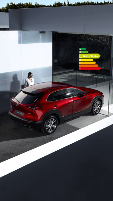 Nouveau Mazda CX-30 rouge vu de dessus et stationné à côté d’une femme.