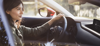 Mulher ao volante do Mazda CX-30 a circular numa estrada.