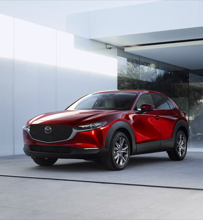 Предната част на Mazda CX-30, паркирана пред стъклена врата.