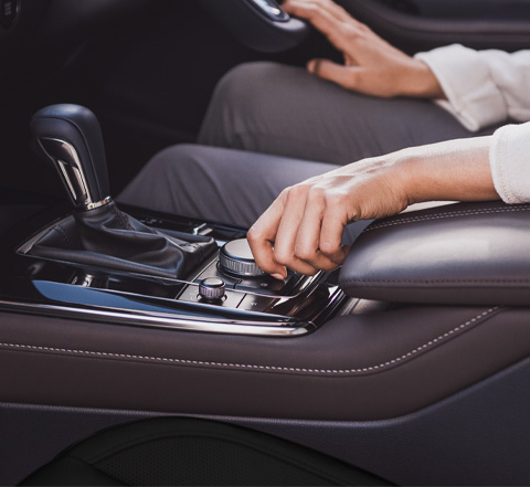 A woman’s hand using the HMI Commander dial with her arm resting on the wide centre armrest.