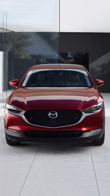 The front view of the new Mazda CX-30 in red parked inside a building.