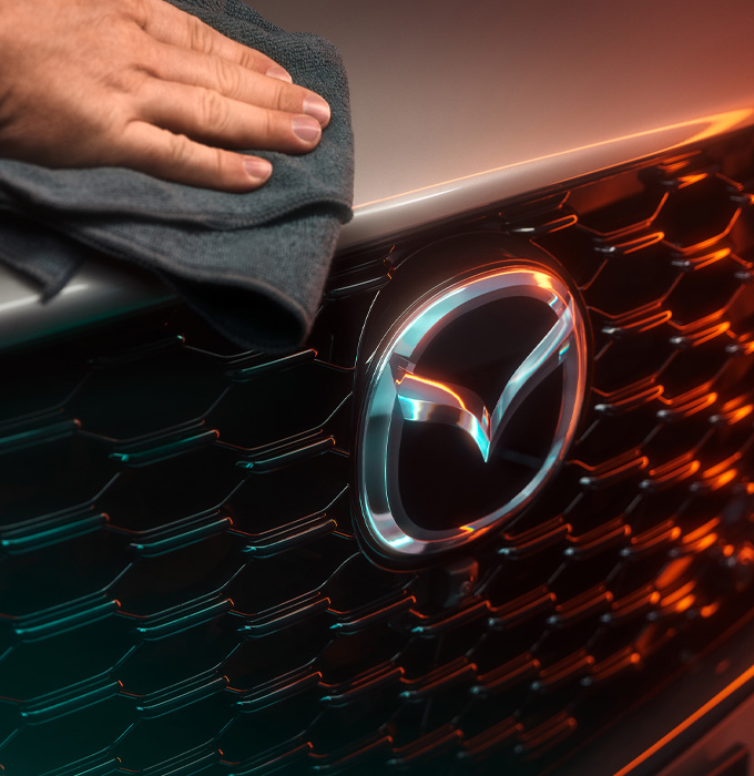 person cleaning the grille of a mazda car aftersales service