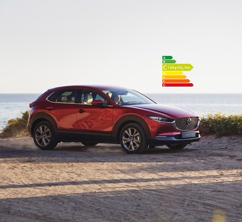 Le nouveau Mazda CX-30 rouge vu de profil, stationné au bord d’une plage.