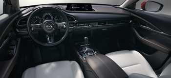 Zicht op het interieur van de Mazda CX-30 met de zetels vooraan en het dashboard.