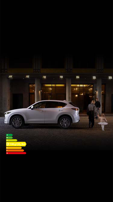 Couple amenant son enfant à un ballet de danse avec un Mazda CX-5 blanc stationné dans la rue.