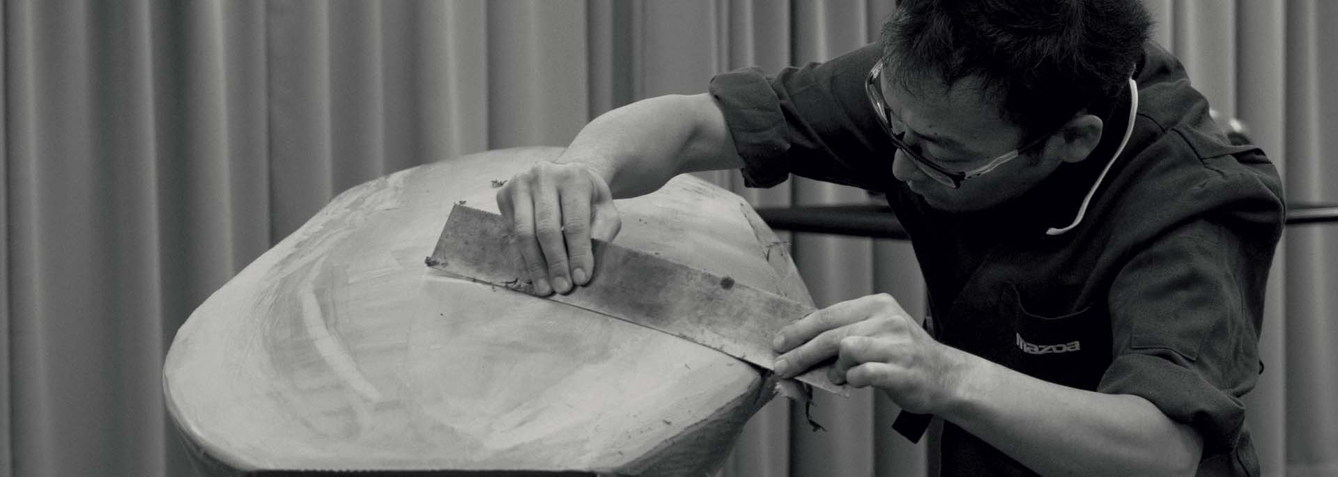 Un maestro artigiano Mazda che crea un modello in argilla a mano.