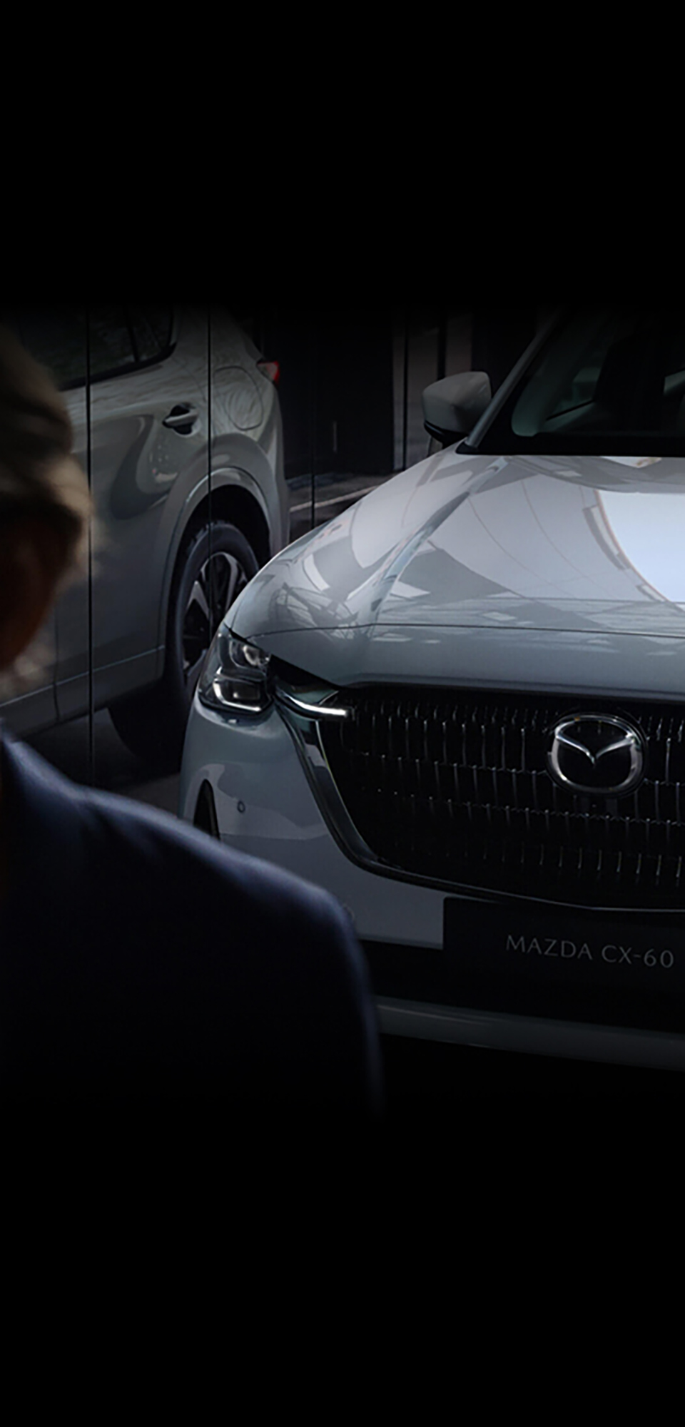 Der neue Mazda CX-60 Plug-in-Hybrid-SUV von vorne, wie er sich in einer Fensterscheibe spiegelt
