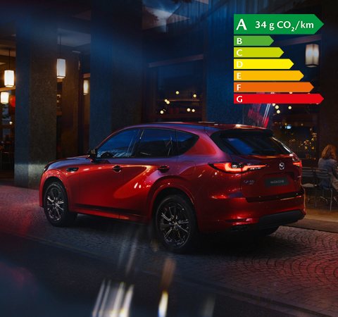 Le nouveau SUV hybride rechargeable Mazda CX-60, vu de l’arrière, stationné de nuit dans une ville.