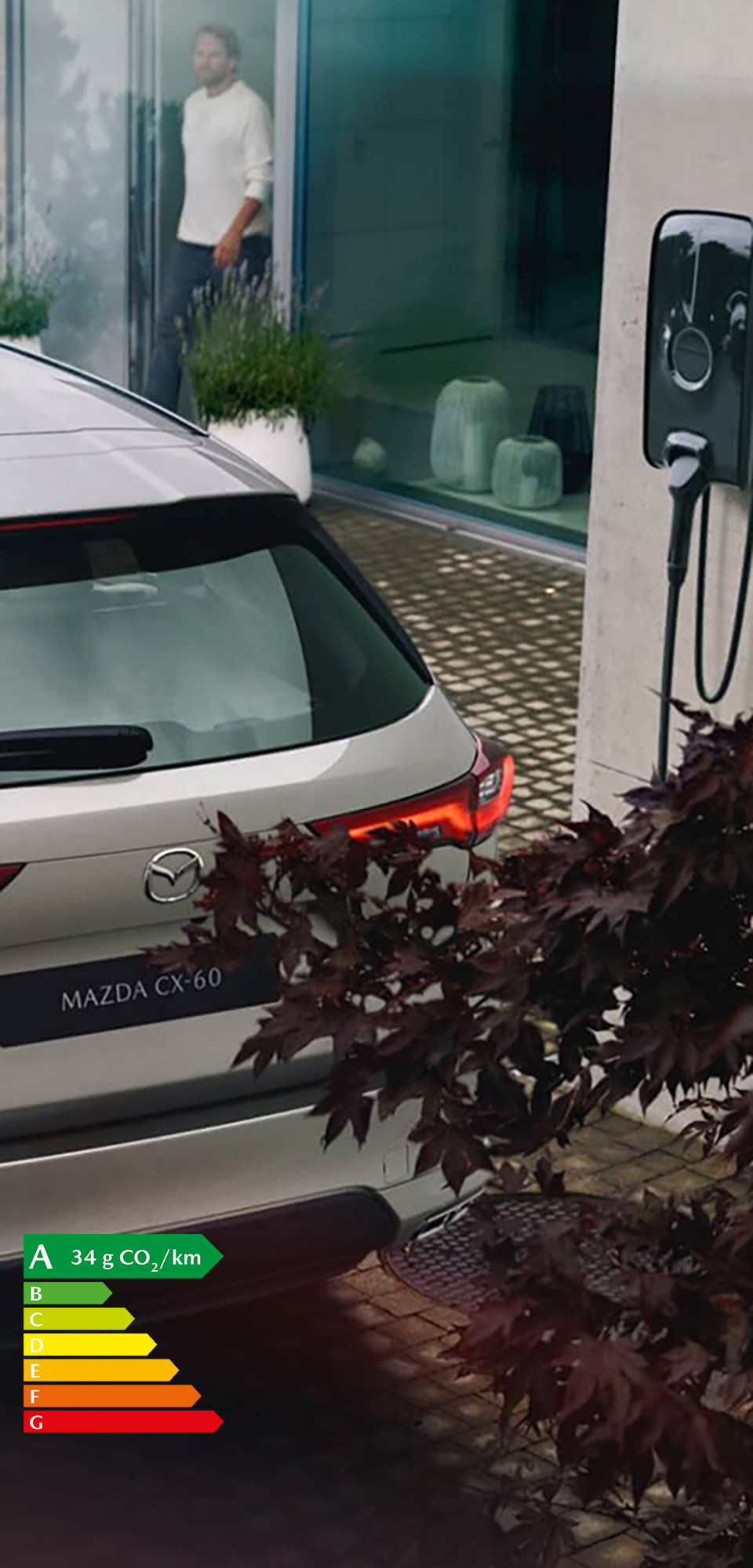 Le nouveau SUV hybride rechargeable Mazda CX-60 stationné à proximité d’une wallbox pour une recharge à domicile.
