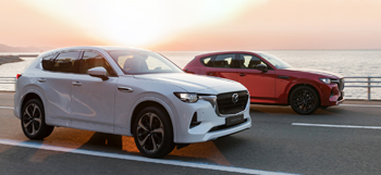 Zwei neue Mazda CX-60 Plug-in Hybrid SUVs fahren auf der Autobahn.