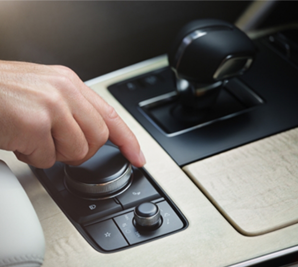 Περιστροφικό κουμπί χειρισμού της μονάδας ελέγχου HMI στο Mazda CX-60 στην κονσόλα από ξύλο σφενδάμου