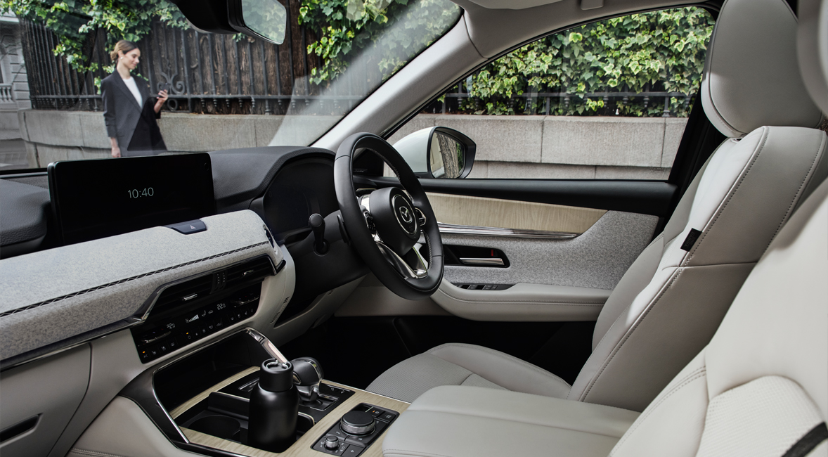 A city street shown from the passenger's point of view inside the Mazda CX-60 Plug-In Hybrid SUV. 