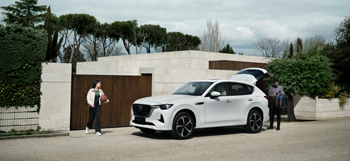 A white Mazda CX-60 Plug-In Hybrid parked with a man and a girl with a basketball standing outside.