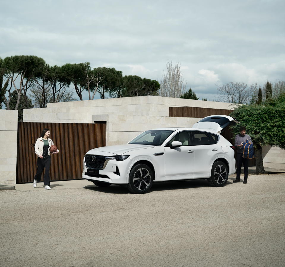 A white Mazda CX-60 Plug-In Hybrid parked with a man and a girl with a basketball standing outside.