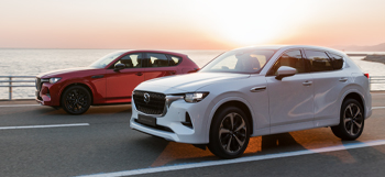 Two all-new Mazda CX-60 Plug-In Hybrid SUVs driving down the highway.