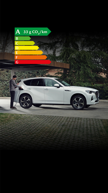 Un SUV hybride rechargeable Mazda CX-60 blanc stationné devant une maison moderne avec beaucoup d’arbres tout autour.