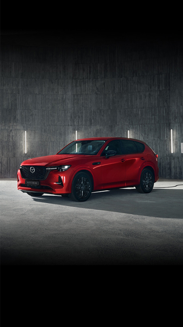 Prie šiuolaikiško statinio pastatytas raudonas „Mazda CX-60 Plug-In Hybrid“ SUV.