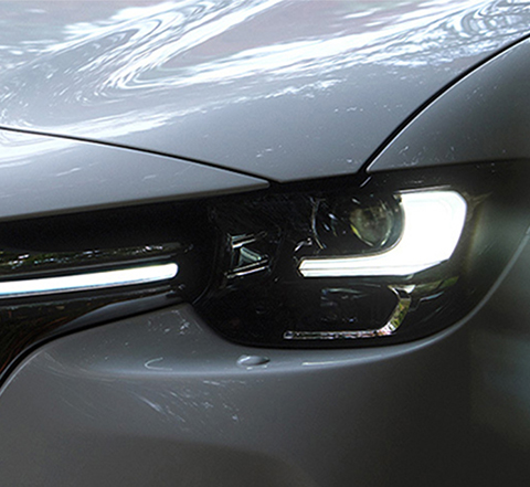 Mohutnú mriežku chladiča úplne nového SUV Mazda CX-60 s kultovým tvarom krídel zvýrazňujú natiahnuté LED svetlomety.