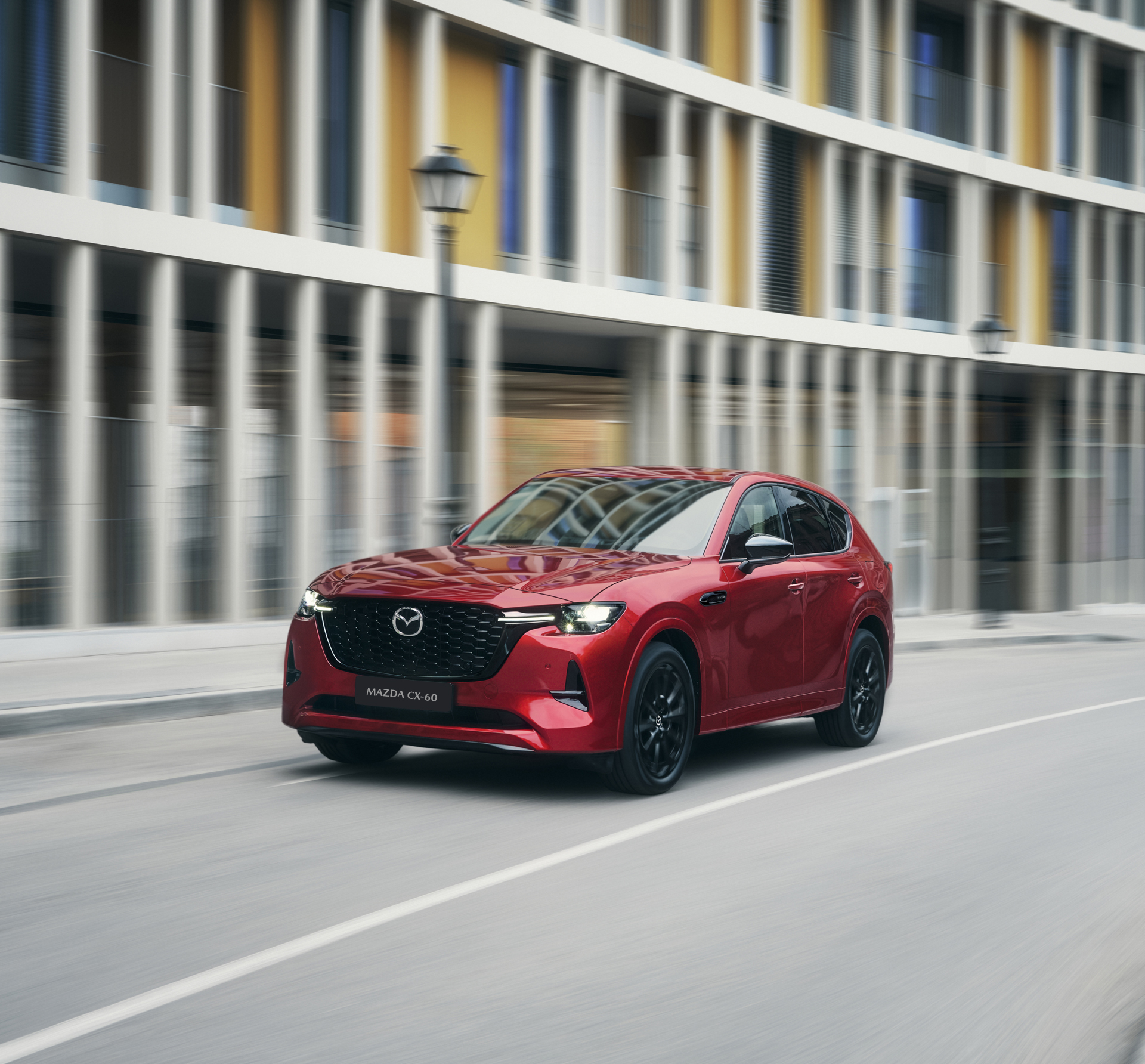 Červená Mazda CX-60, plug-in hybridní SUV, projíždějící zatáčkou na dálnici.