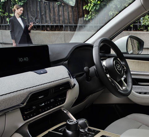 A city street shown from the passenger's point of view inside the Mazda CX-60 Plug-In Hybrid SUV. 