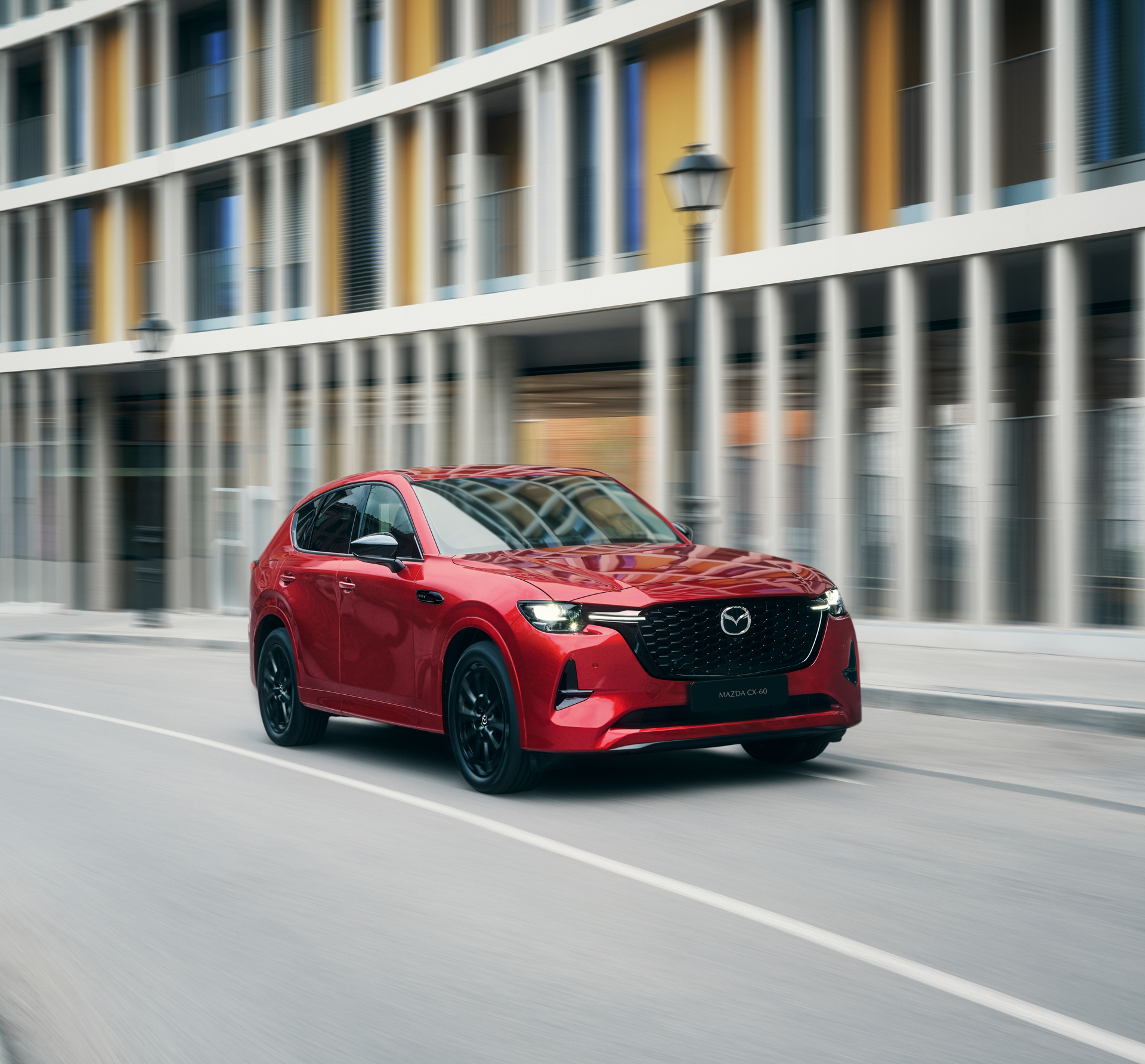 A red Mazda CX-60 Plug-In Hybrid SUV driving around a curve on highway.