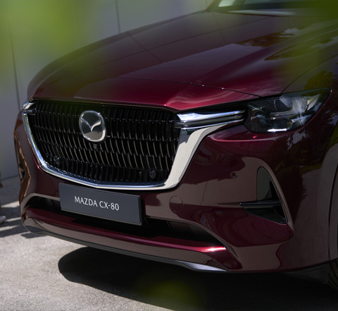 Преден изглед на Mazda CX-80 SUV в червен цвят с нейните лого и име.