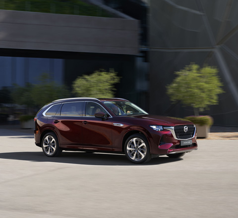 Ein roter Mazda CX-80 Crossover mit Allradantrieb fährt auf der Strasse.