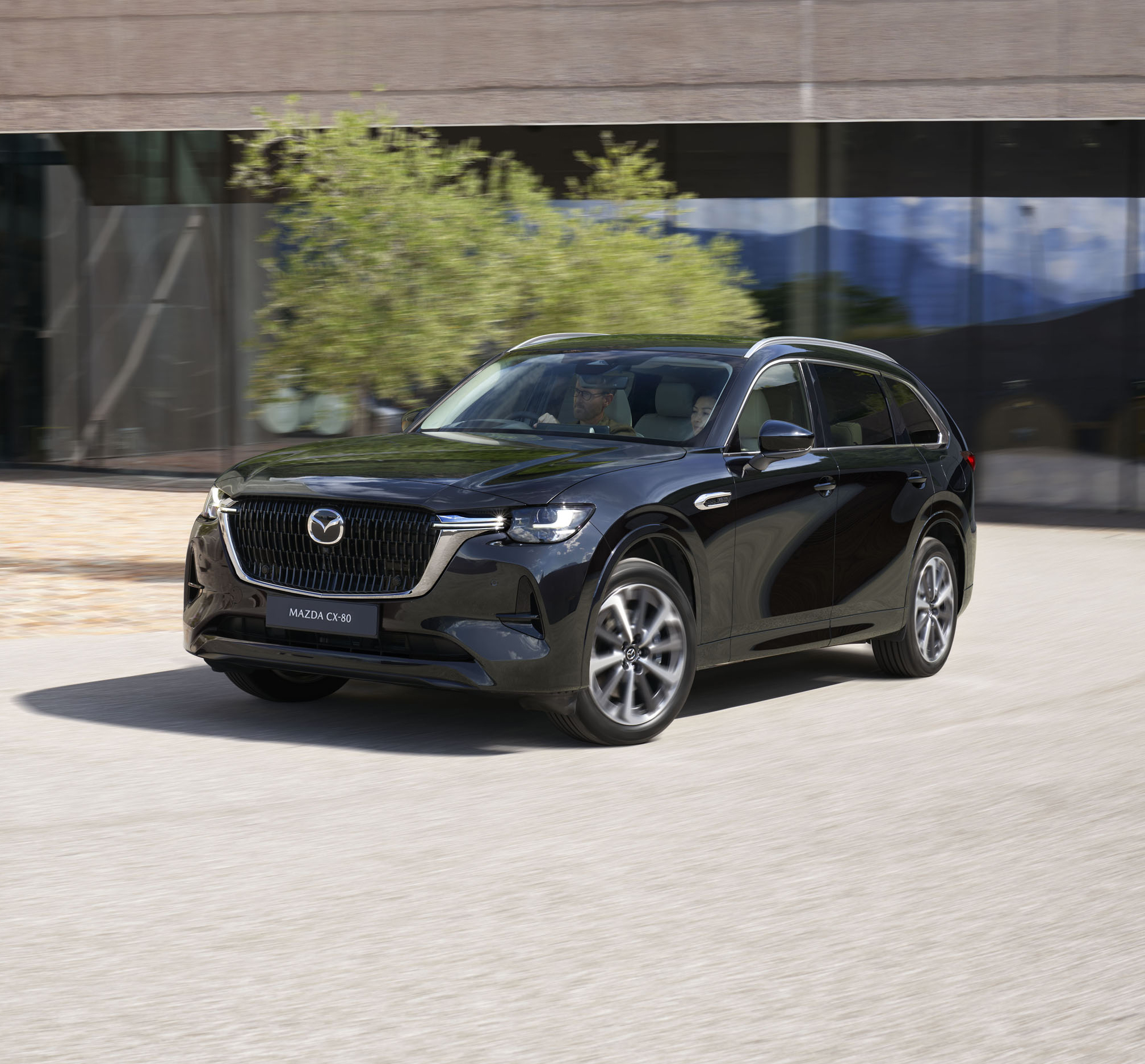 A black Mazda CX-80 parked in front of a building.