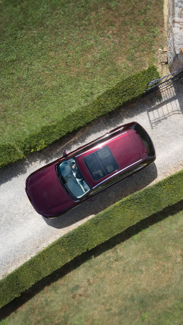 The Mazda CX-80 SUV pictured from above parked in a street between two grass walls.