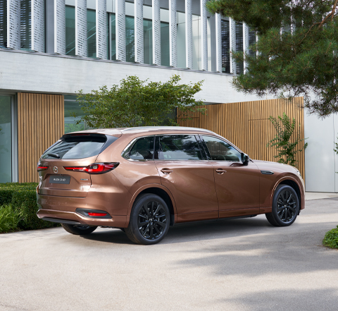 The back view of the Mazda CX-80 SUV parked in front of a house.